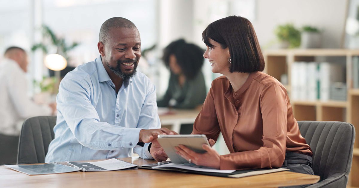 Financial advisor discussing options with a client, reviewing a tablet in a modern office—RIA E&O insurance consultation.
